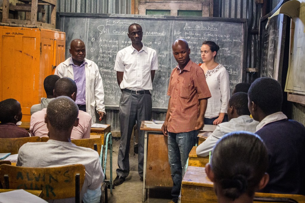 Charles Ogutu (v červenej košeli) v jednej z tried, kde prebieha kurz pre dospelých, ktorí so dokončujú základné vzdelanie. Na fotke sa prihovára študentom počas návštevy Koordinátorky Dobrej noviny. 